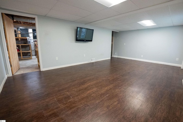 finished below grade area featuring baseboards, a drop ceiling, and wood finished floors