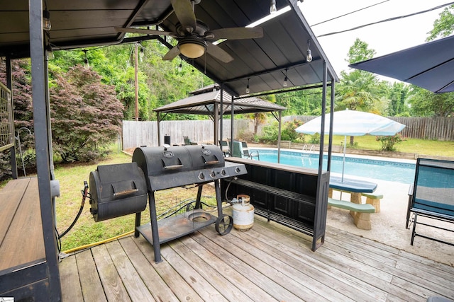 wooden deck with a gazebo, a fenced in pool, a ceiling fan, and a fenced backyard
