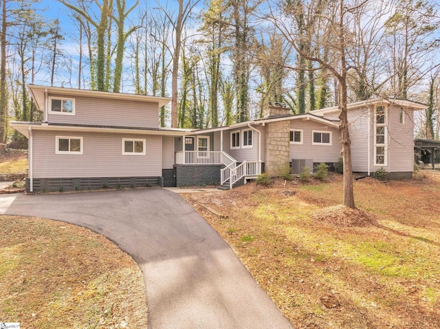 view of front of house with covered porch, crawl space, a chimney, central AC, and aphalt driveway