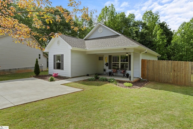 view of front of home with fence, a shingled roof, a patio area, and a front lawn
