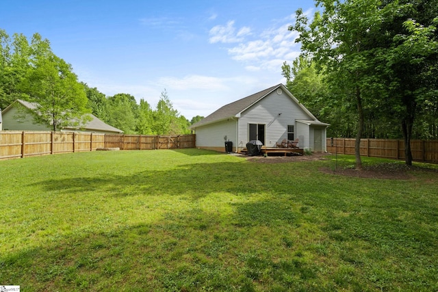rear view of property featuring a yard, a deck, and a fenced backyard