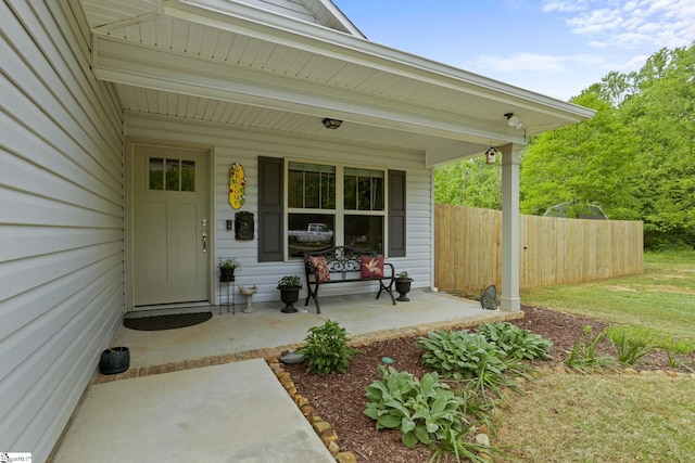 entrance to property featuring fence and covered porch