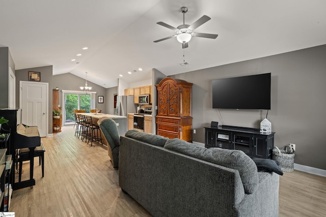 living area featuring baseboards, light wood finished floors, ceiling fan with notable chandelier, and lofted ceiling