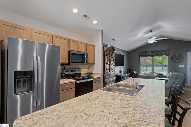 kitchen featuring a sink, light countertops, stainless steel appliances, lofted ceiling, and a kitchen bar