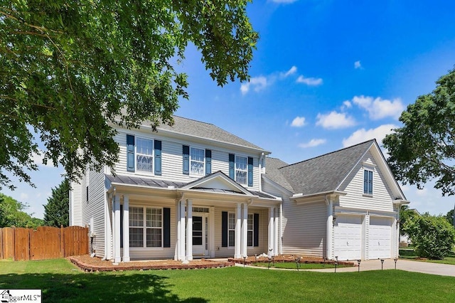 view of front of house with fence, covered porch, a front yard, a standing seam roof, and driveway