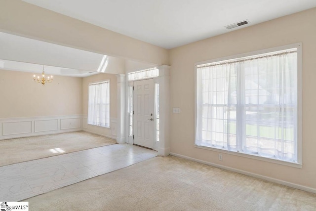 carpeted foyer entrance with an inviting chandelier and visible vents