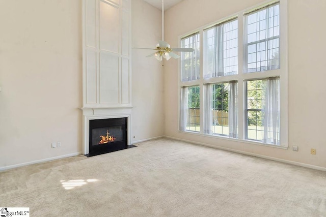 unfurnished living room featuring a fireplace, baseboards, carpet, and a towering ceiling