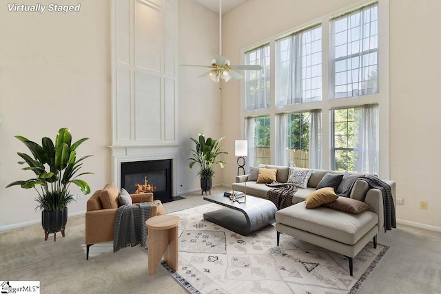 sitting room with a large fireplace, a high ceiling, light carpet, and baseboards
