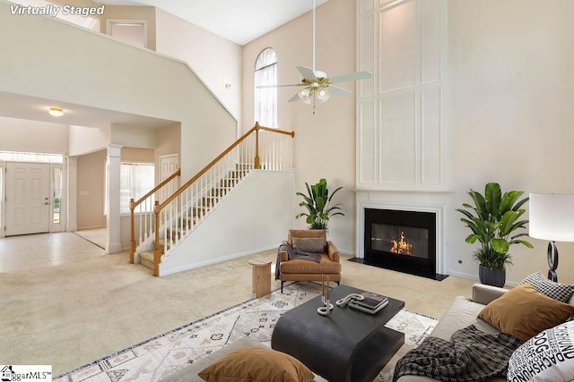 living room with a ceiling fan, a high ceiling, light carpet, and stairway