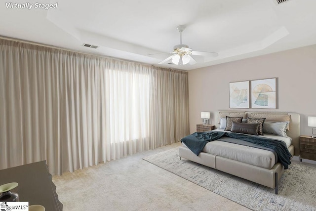 bedroom featuring carpet floors, a ceiling fan, a tray ceiling, and visible vents