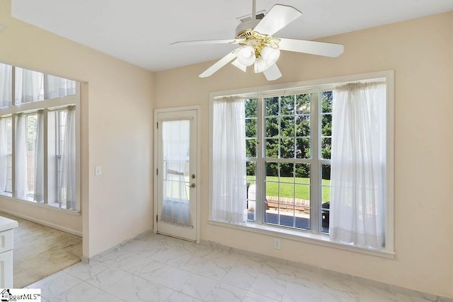 entryway with a healthy amount of sunlight, a ceiling fan, and marble finish floor