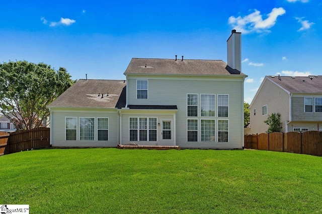 back of house featuring a fenced backyard, a chimney, and a yard