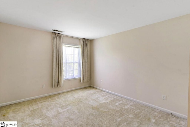 carpeted spare room featuring baseboards and visible vents