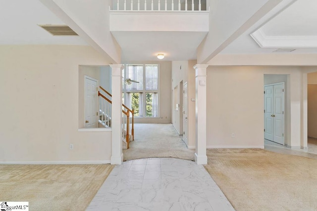carpeted foyer entrance featuring marble finish floor, baseboards, decorative columns, visible vents, and stairway