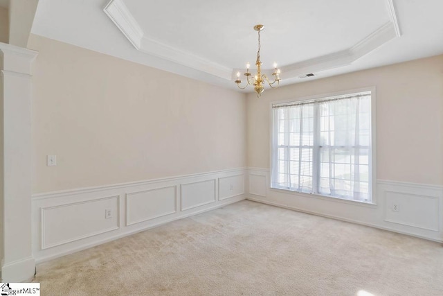 empty room with wainscoting, a chandelier, ornamental molding, and a raised ceiling