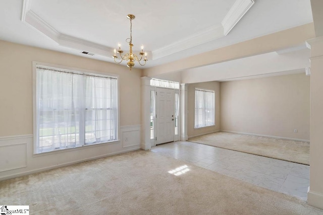 foyer entrance with an inviting chandelier, ornamental molding, a tray ceiling, and visible vents