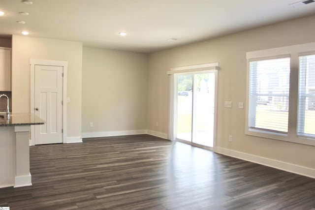 unfurnished living room with baseboards, recessed lighting, and dark wood-style flooring