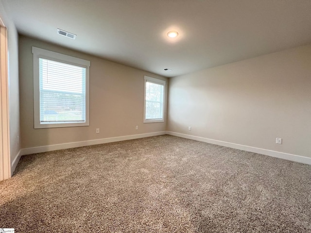 carpeted spare room with visible vents and baseboards