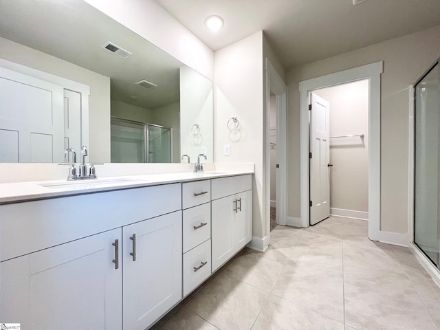 bathroom with a sink, double vanity, baseboards, a shower stall, and visible vents