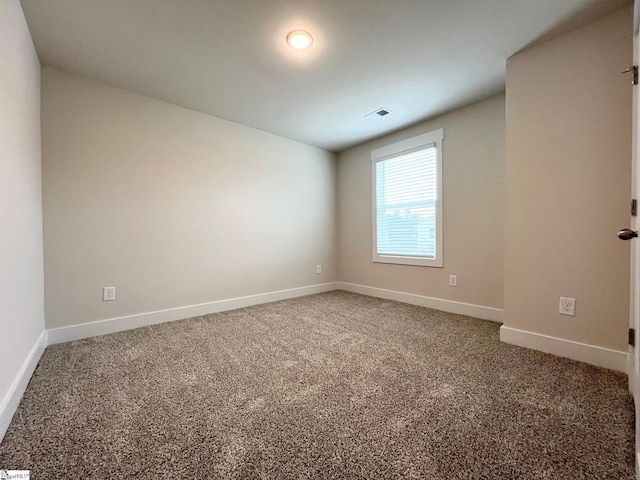 carpeted empty room featuring baseboards and visible vents