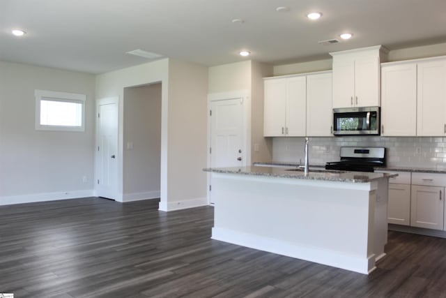 kitchen with a kitchen island with sink, stainless steel appliances, baseboards, tasteful backsplash, and dark wood-style floors