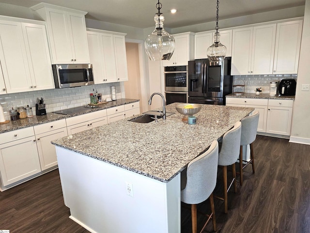 kitchen featuring appliances with stainless steel finishes, dark wood-style floors, a sink, and tasteful backsplash