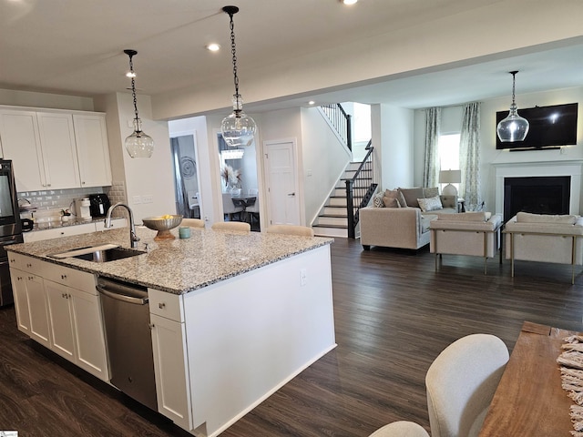 kitchen featuring stainless steel dishwasher, open floor plan, dark wood finished floors, and a sink