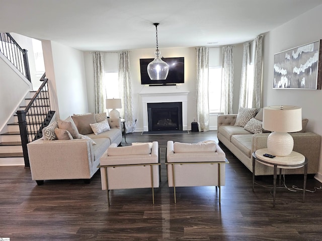 living room featuring stairs, dark wood-style floors, and a fireplace