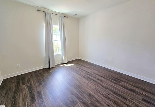 spare room featuring baseboards and dark wood-style floors