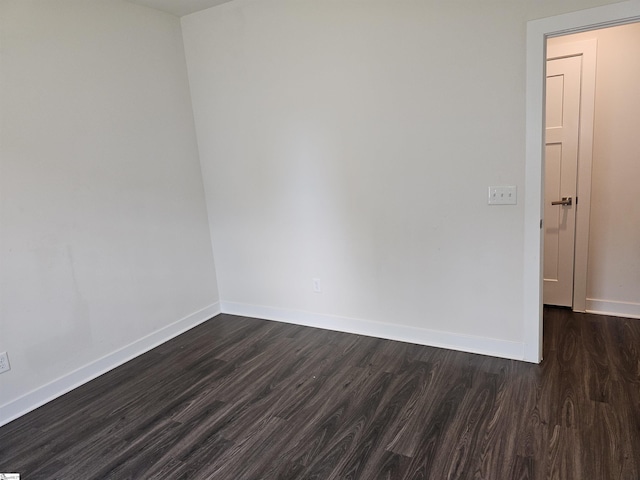 empty room featuring baseboards and dark wood-style flooring