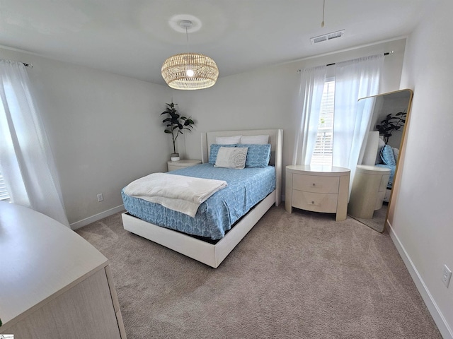 bedroom with baseboards, light carpet, and visible vents