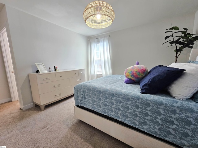 bedroom featuring baseboards, light carpet, and an inviting chandelier