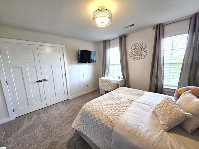 carpeted bedroom featuring baseboards, a closet, and visible vents