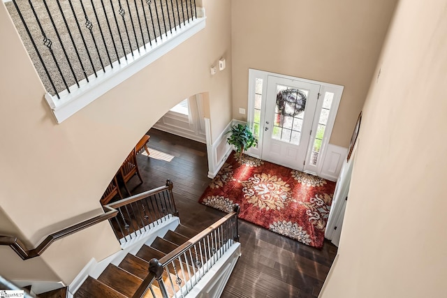 foyer featuring arched walkways, stairs, a high ceiling, and hardwood / wood-style floors