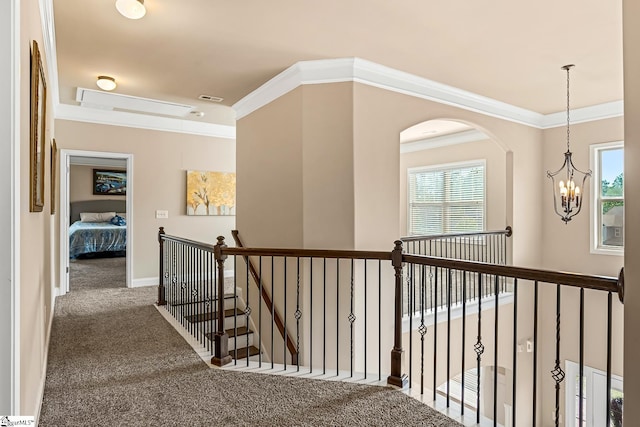 hall with plenty of natural light, ornamental molding, carpet flooring, and an upstairs landing