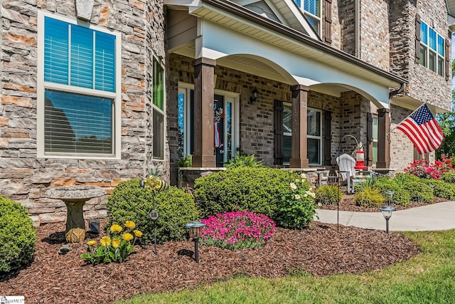 property entrance with covered porch and stone siding