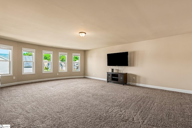 unfurnished living room featuring baseboards and carpet flooring