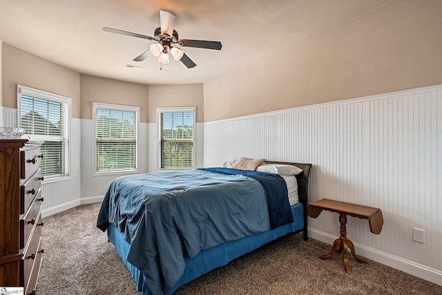 bedroom with visible vents, baseboards, a wainscoted wall, a ceiling fan, and carpet