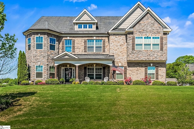 craftsman inspired home with covered porch, a front lawn, and brick siding