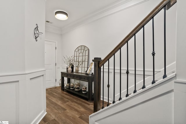 entrance foyer with a decorative wall, wood finished floors, visible vents, ornamental molding, and stairway