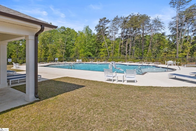 community pool featuring a lawn, fence, and a patio area