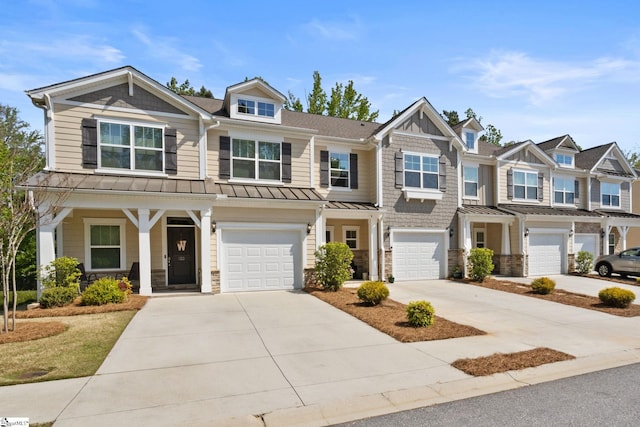 view of front facade featuring an attached garage, a standing seam roof, driveway, and stone siding