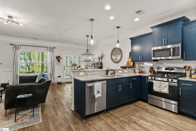 kitchen with appliances with stainless steel finishes, a sink, a peninsula, open floor plan, and visible vents