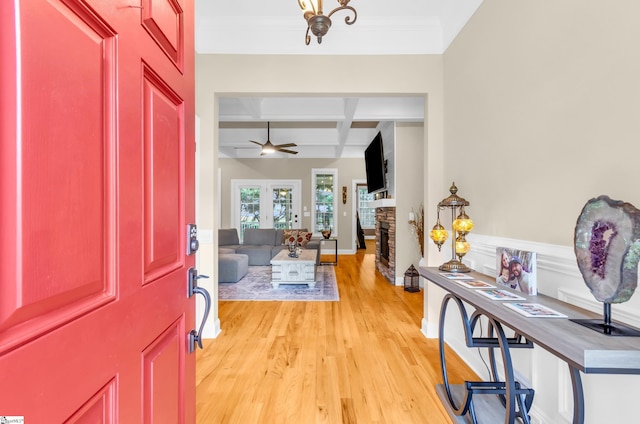 foyer entrance with ceiling fan, a fireplace, beam ceiling, light wood finished floors, and coffered ceiling