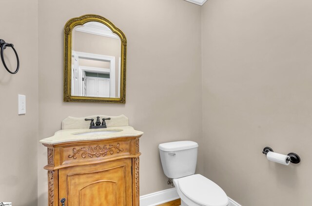 half bath featuring vanity, baseboards, and toilet