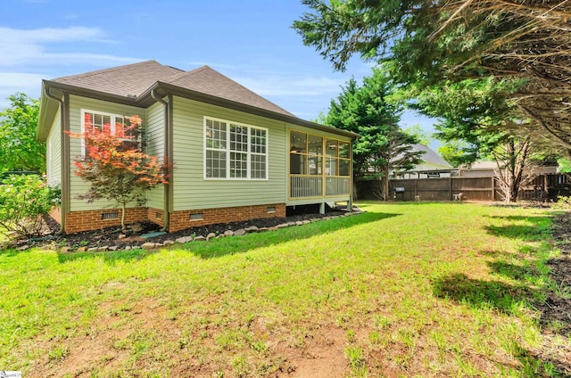 view of side of home featuring fence, a sunroom, a shingled roof, crawl space, and a yard
