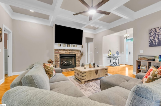 living room with light wood finished floors, ceiling fan with notable chandelier, beam ceiling, and coffered ceiling