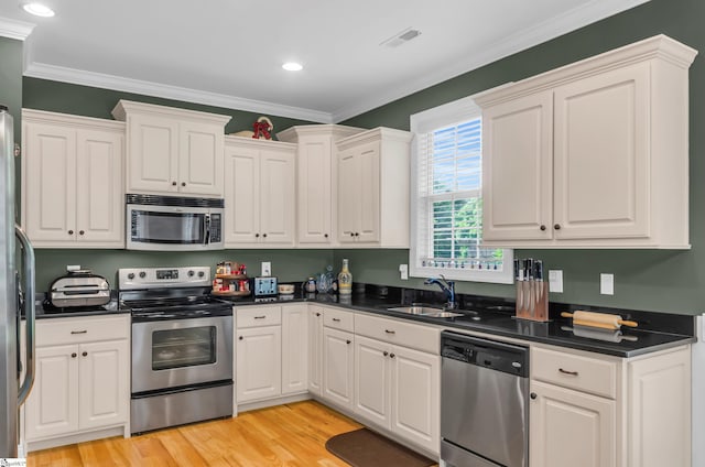 kitchen with a sink, appliances with stainless steel finishes, white cabinets, and dark countertops