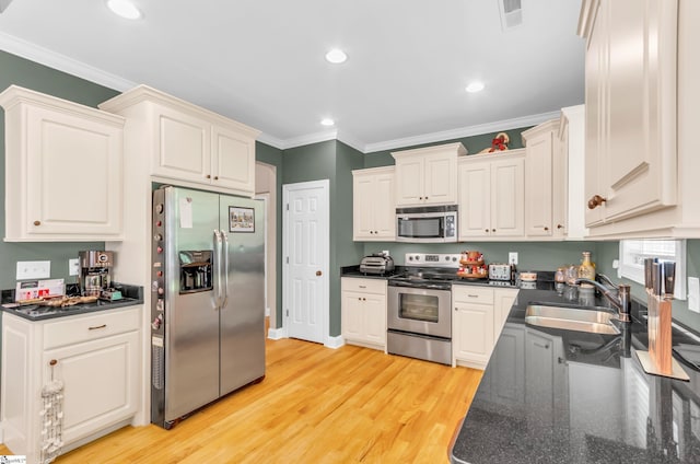kitchen featuring visible vents, appliances with stainless steel finishes, dark countertops, a sink, and ornamental molding