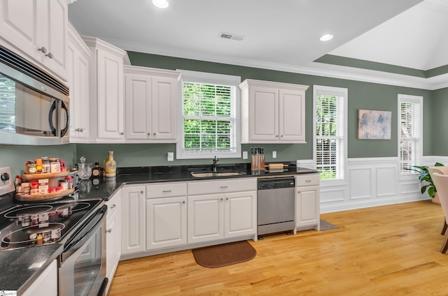 kitchen featuring crown molding, white cabinets, appliances with stainless steel finishes, a sink, and visible vents